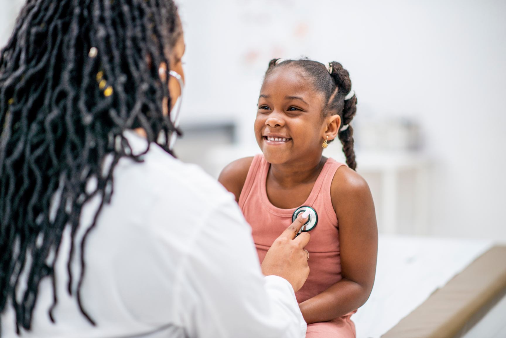 Pediatra ausculta una bambina sorridente con lo stetoscopio